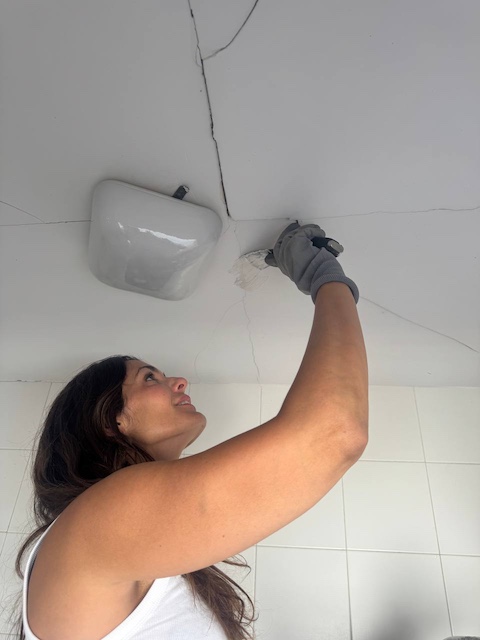 Gema aplicando masilla en el techo del baño