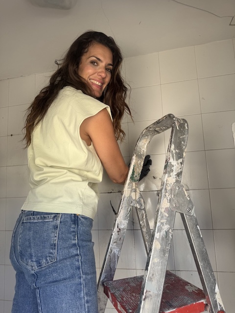 Gema limpiando azulejos subida en una escalera