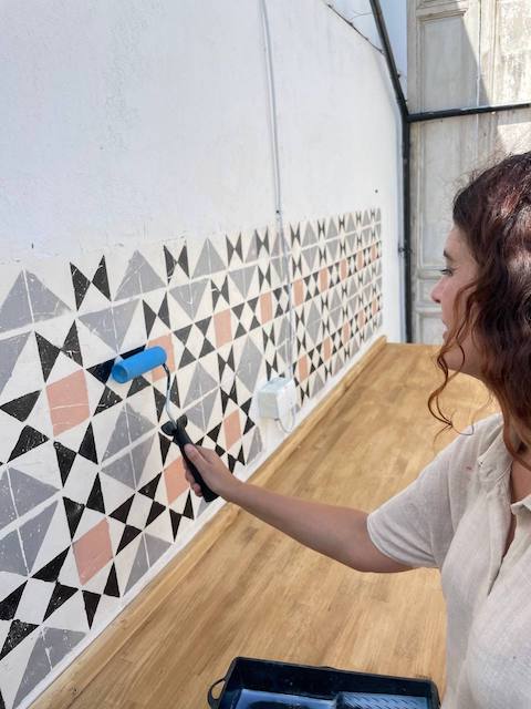 Gema barnizando el zócalo de la cocina de exterior pintada