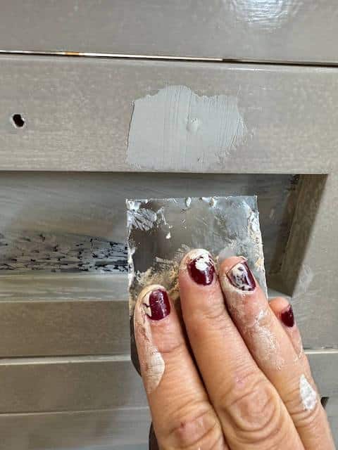 Tapamos con masilla los agujeros del pomo del mueble del lavabo que vamos a pintar