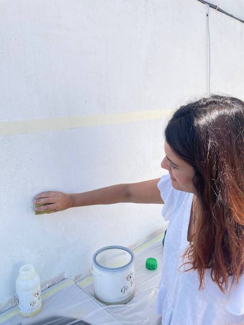 Gema limpiando la pared de la cocina exterior donde haremos el zócalo con masilla