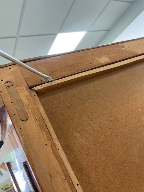 Desmontamos la parte trasera de la vitrina que vamos a pintar con un destornillador
